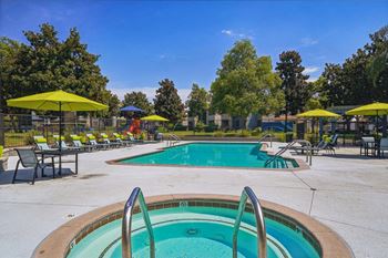 A pool with a hot tub and sun loungers.